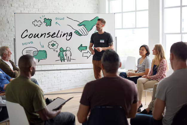 A facilitated counselling group gathered around a whiteboard